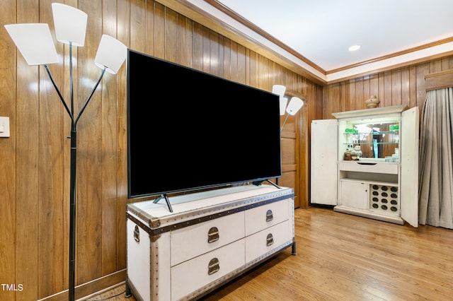 unfurnished living room featuring ornamental molding, wood walls, and light wood-type flooring