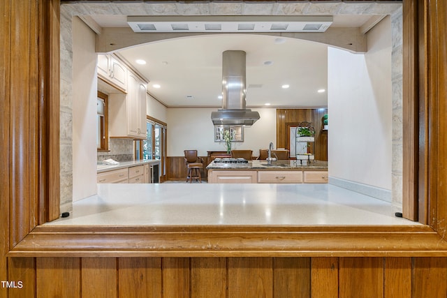 kitchen with kitchen peninsula, backsplash, stainless steel gas cooktop, sink, and island exhaust hood