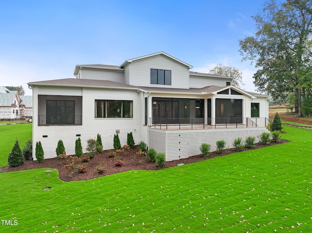 view of front of home with roof with shingles, a front yard, and a sunroom