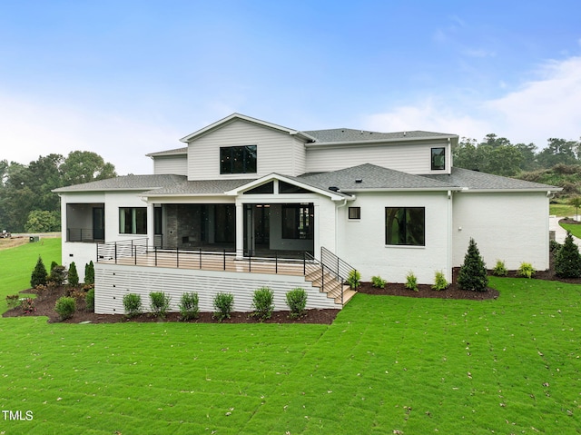 back of property with a yard, a shingled roof, and a sunroom