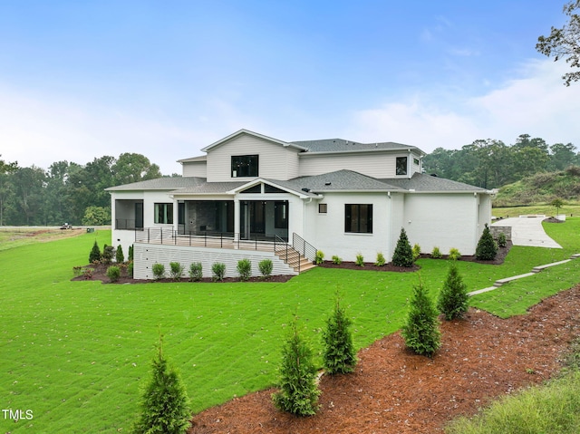 rear view of property featuring a sunroom, roof with shingles, and a yard