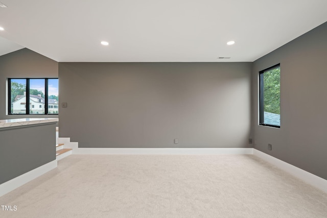 spare room featuring recessed lighting, light colored carpet, and baseboards