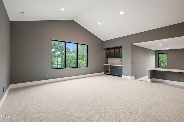 unfurnished living room featuring recessed lighting, light colored carpet, visible vents, baseboards, and indoor wet bar