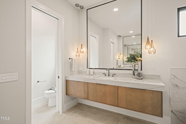 bathroom featuring toilet, recessed lighting, baseboards, and vanity