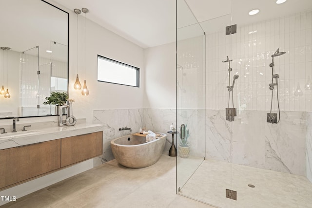 full bathroom with vanity, a freestanding tub, tile walls, and a shower stall