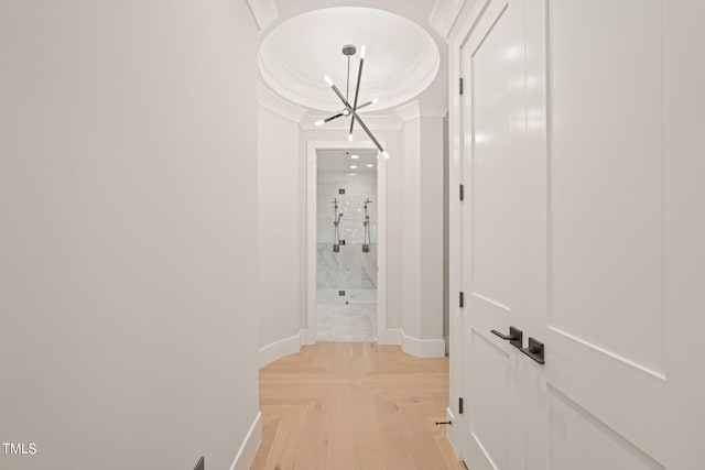 hallway with a notable chandelier, ornamental molding, and baseboards