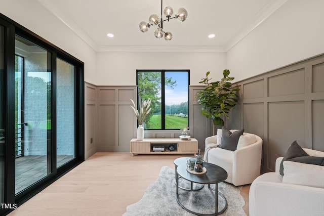 living area with ornamental molding, light wood-type flooring, a notable chandelier, and a decorative wall