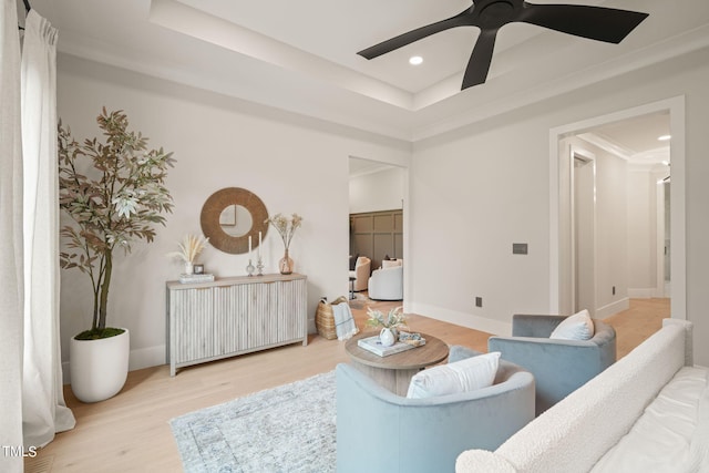 living room featuring baseboards, a tray ceiling, and wood finished floors