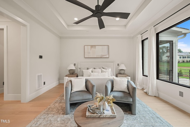 bedroom with a tray ceiling, light wood-style flooring, visible vents, and recessed lighting