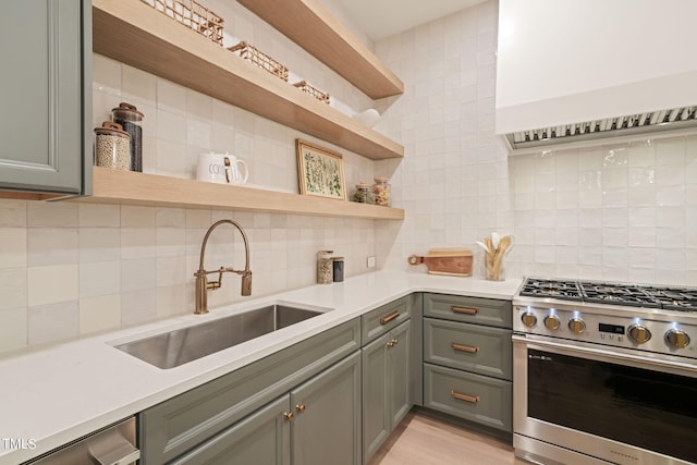 kitchen with a sink, light countertops, stainless steel range with gas cooktop, decorative backsplash, and open shelves