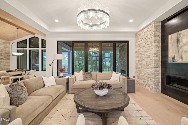 living area with light wood-style floors, a fireplace, recessed lighting, and a notable chandelier