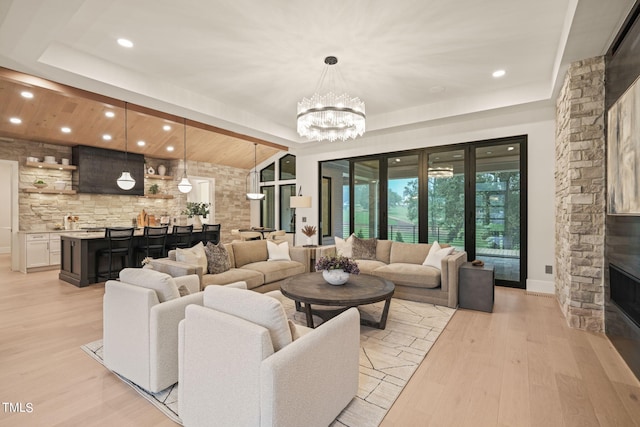 living area featuring an inviting chandelier, vaulted ceiling, light wood-style floors, a fireplace, and recessed lighting