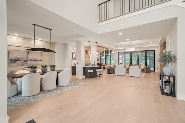 living area with light wood-style floors, a tray ceiling, an inviting chandelier, and recessed lighting