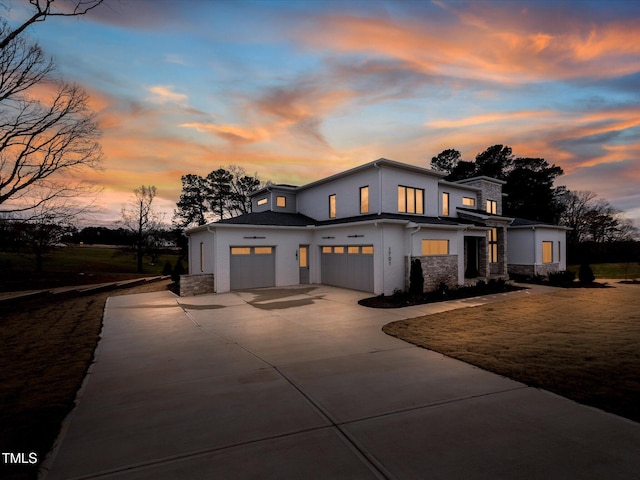 view of front of house featuring driveway, stone siding, stucco siding, an attached garage, and a front yard