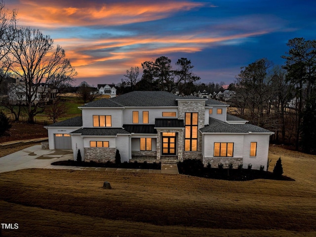 view of front of home with metal roof, concrete driveway, stone siding, a standing seam roof, and a front yard