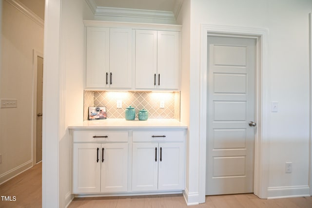 bar featuring crown molding, white cabinets, light wood-type flooring, and tasteful backsplash