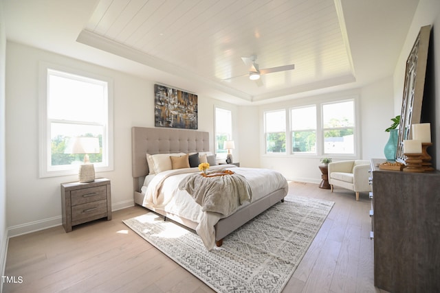 bedroom featuring multiple windows, a raised ceiling, and wood-type flooring