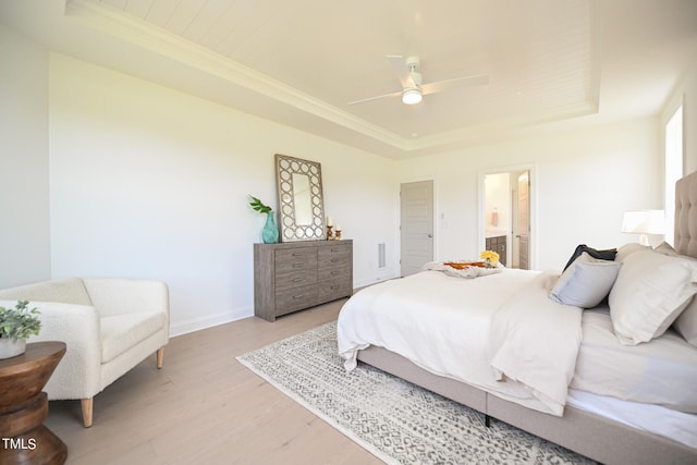 bedroom featuring a tray ceiling, ceiling fan, connected bathroom, and wood-type flooring