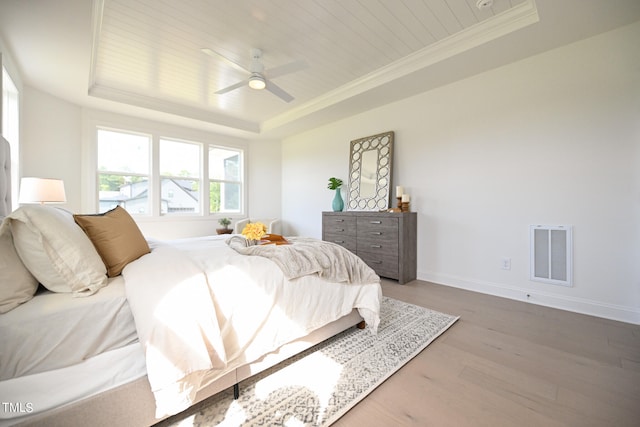 bedroom featuring ceiling fan, a raised ceiling, and hardwood / wood-style floors