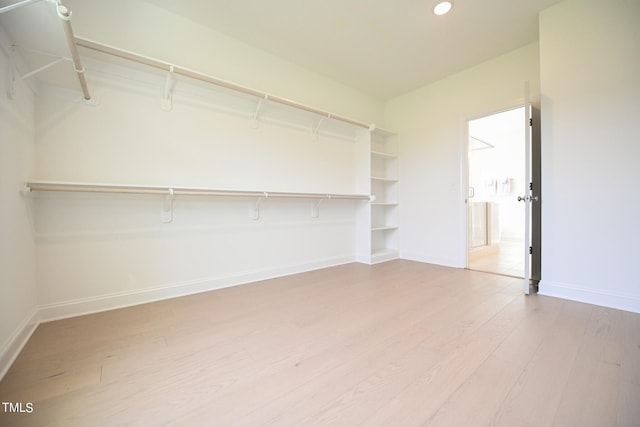 walk in closet with light hardwood / wood-style flooring