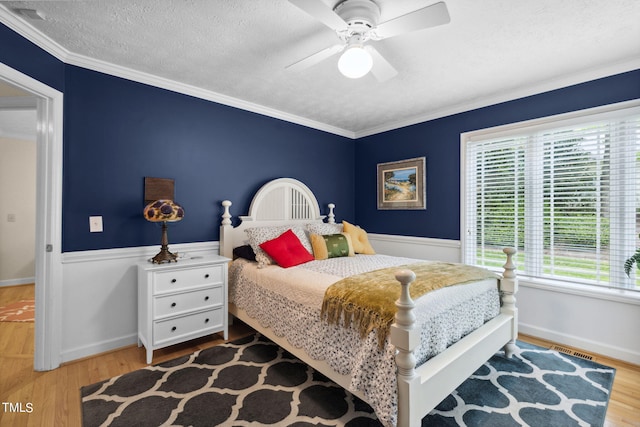 bedroom with crown molding, wood-type flooring, ceiling fan, and a textured ceiling