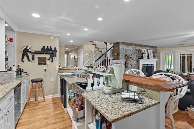 kitchen featuring light stone counters, white cabinets, a fireplace, and light wood-type flooring