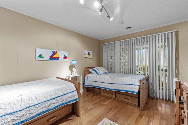 bedroom with light hardwood / wood-style flooring, rail lighting, and a textured ceiling