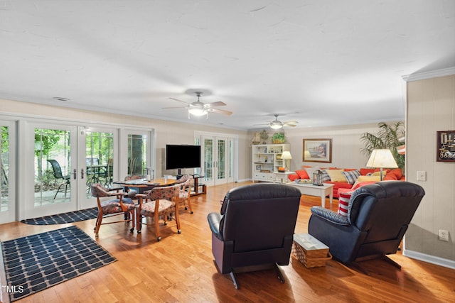 living room with french doors, crown molding, ceiling fan, and light wood-type flooring