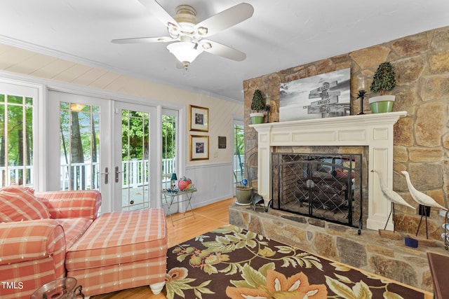 living room featuring french doors, ceiling fan, hardwood / wood-style flooring, a fireplace, and ornamental molding