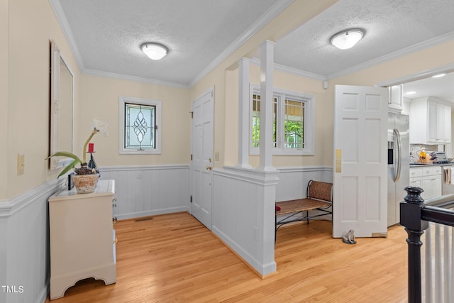 foyer entrance with a textured ceiling, light hardwood / wood-style floors, and crown molding