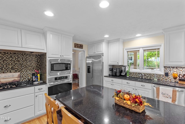 kitchen with backsplash, stainless steel appliances, light wood-type flooring, and white cabinetry