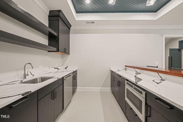 kitchen with light stone counters, a raised ceiling, appliances with stainless steel finishes, and sink