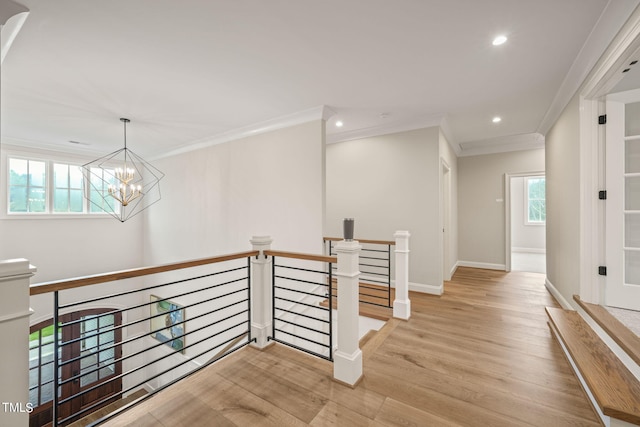 hallway with ornamental molding, an inviting chandelier, and light hardwood / wood-style floors