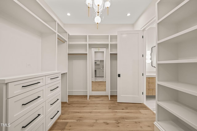 walk in closet with an inviting chandelier and light hardwood / wood-style flooring