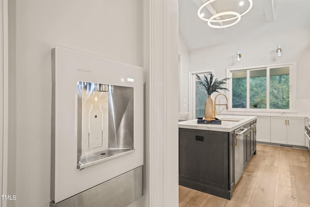 kitchen with dishwasher, light hardwood / wood-style floors, an island with sink, white cabinets, and hanging light fixtures