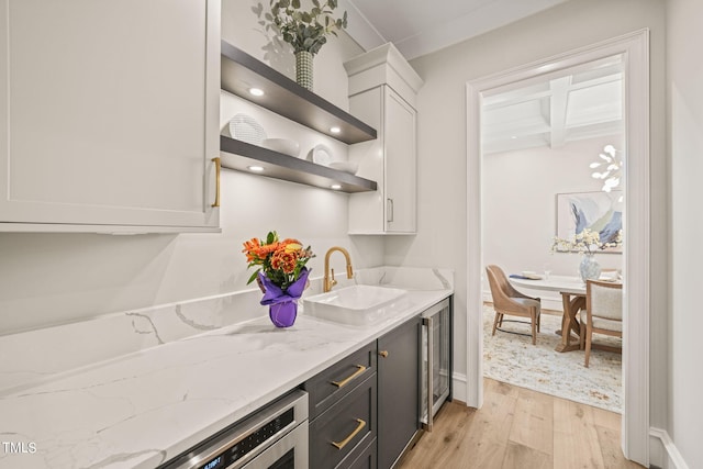 kitchen featuring light stone countertops, light hardwood / wood-style floors, sink, and white cabinets