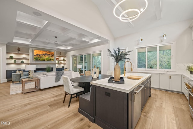 kitchen with a center island with sink, ceiling fan with notable chandelier, light hardwood / wood-style floors, and white cabinetry