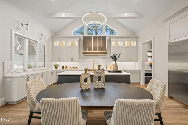 dining space featuring a notable chandelier, lofted ceiling with beams, and light hardwood / wood-style floors