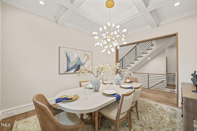 dining space with light wood-type flooring, coffered ceiling, and an inviting chandelier