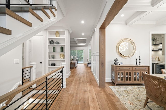 hall featuring ornamental molding, beverage cooler, beam ceiling, and light hardwood / wood-style floors