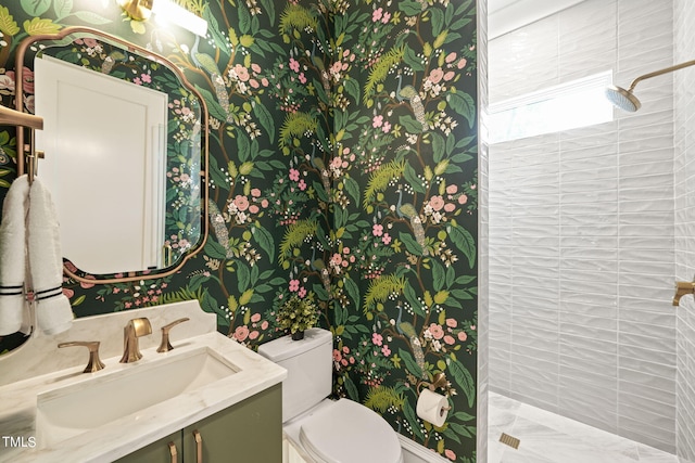 bathroom featuring tiled shower, vanity, and toilet