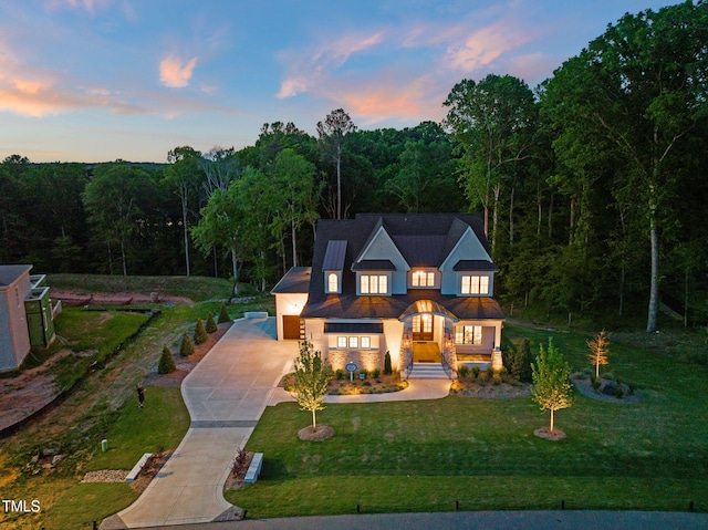 view of front of property featuring a lawn, stucco siding, driveway, and a view of trees