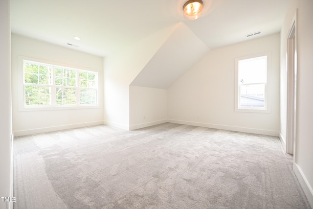 bonus room with light colored carpet and vaulted ceiling