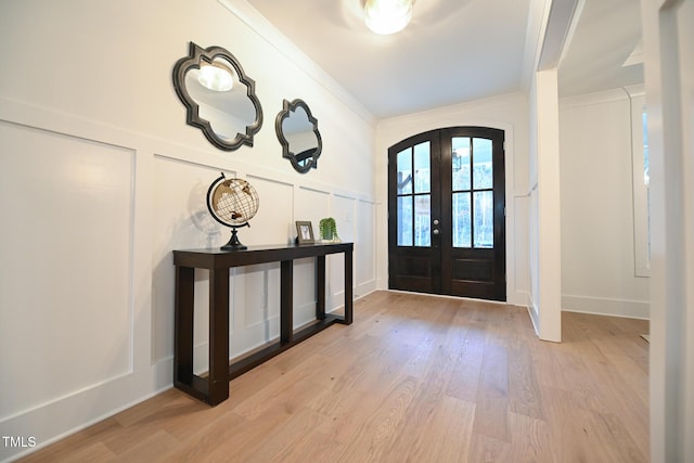 foyer with light wood-type flooring, ornamental molding, and french doors