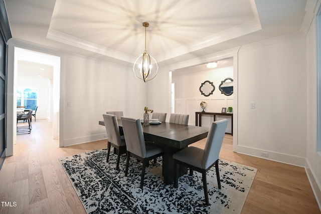 dining room with a tray ceiling, a chandelier, and hardwood / wood-style flooring