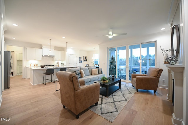 living room with ceiling fan, sink, and light hardwood / wood-style flooring