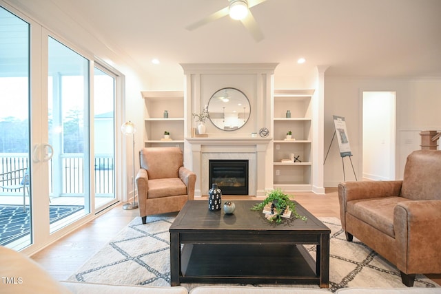 living room with ceiling fan, light hardwood / wood-style floors, ornamental molding, and built in features