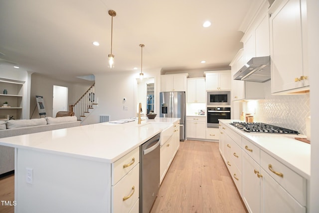 kitchen featuring a large island with sink, light hardwood / wood-style flooring, appliances with stainless steel finishes, and exhaust hood