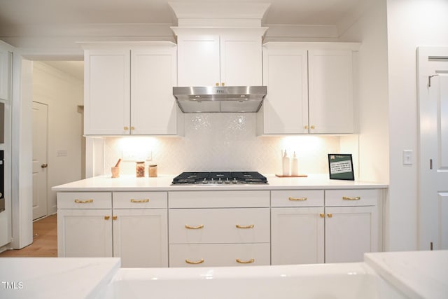 kitchen with tasteful backsplash, white cabinetry, light hardwood / wood-style floors, and stainless steel gas stovetop