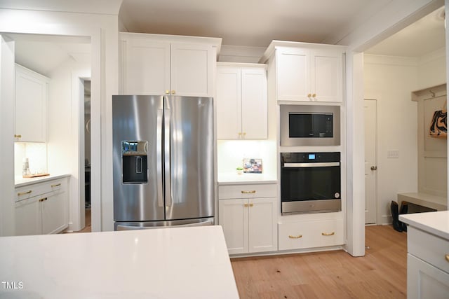 kitchen featuring appliances with stainless steel finishes, light wood-type flooring, white cabinetry, and ornamental molding